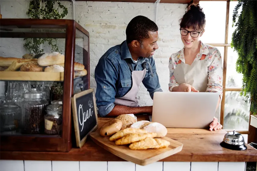 Small business restaurant and bakeshop owners working from a laptop and payment system connected to fast fibre internet Kickstarter Package with SmartBiz from WTC Communications Kingston