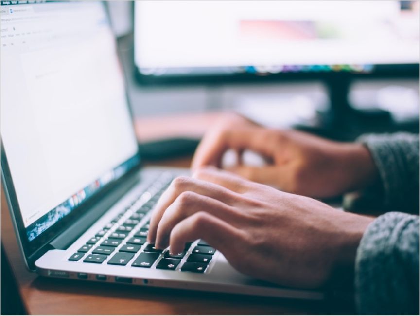 Two hands type on a notebook computer